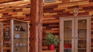 A wooden interior with a wooden bar counter, a potted plant, and a cabinet with glass doors. - Pension Les (Brežice)