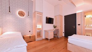A modern bedroom with two beds, a desk, and a TV. - Pension Les (Brežice)