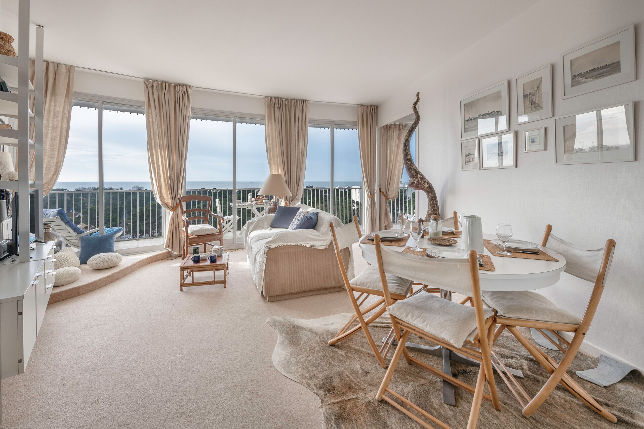A spacious living room with a balcony, a dining area, and a bedroom with a large window.