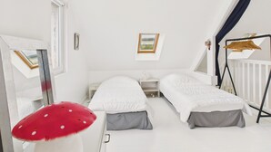 A bedroom with two beds, a window, a small desk, and a hanging chair.