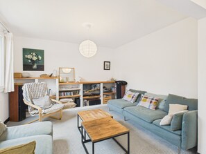 Un salon comprenant un canapé, un fauteuil, une table basse et une bibliothèque.