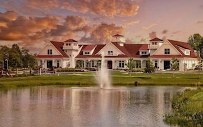 A large, multi-story building with a symmetrical facade, a central fountain, and a well-maintained lawn.