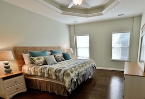 A bedroom with a bed, nightstands, a ceiling fan, and a window with blinds.