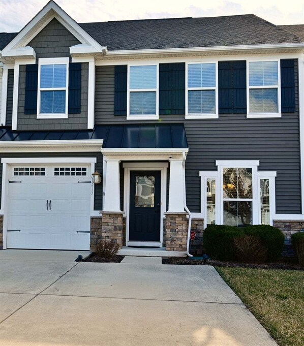 A two-story house with a garage, a front door, and a small porch area.