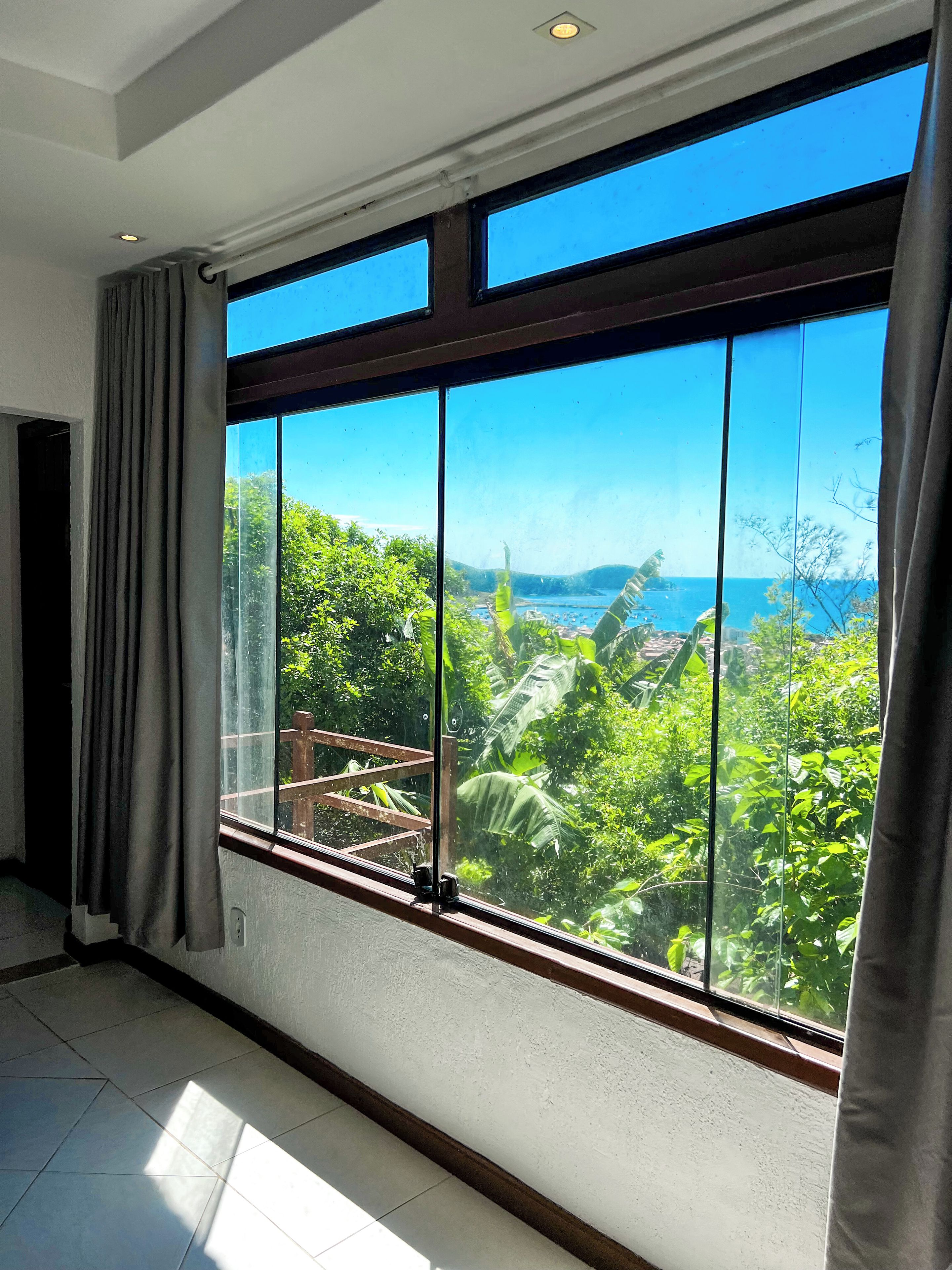 A room with a large window overlooking a lush landscape and a body of water.