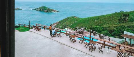 A view of a coastal area with a pool and outdoor seating.