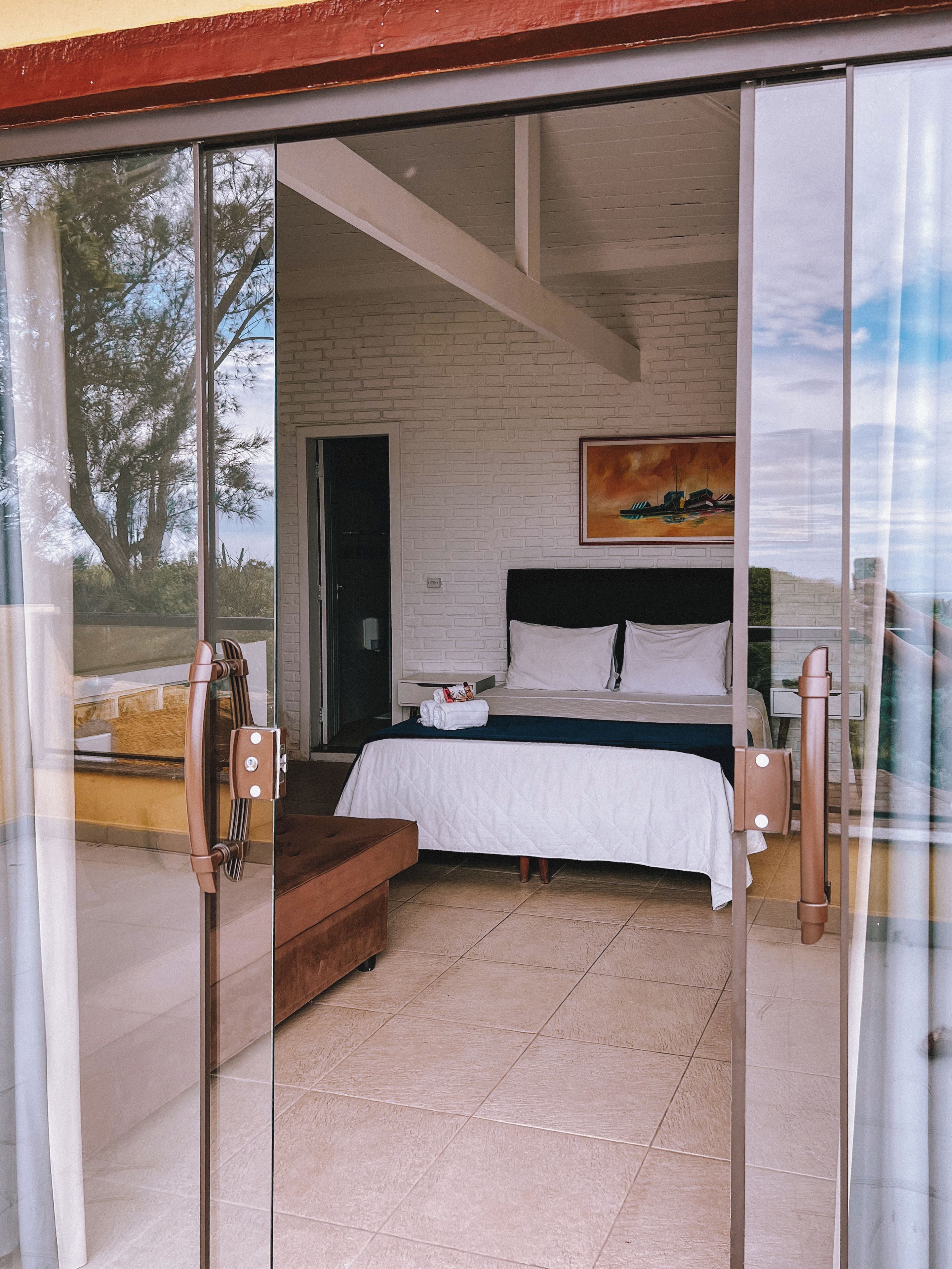 Un dormitorio con cama, un cuadro y vistas a través de un ventanal.