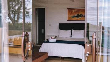 Un dormitorio con cama, un cuadro y vistas a través de un ventanal.