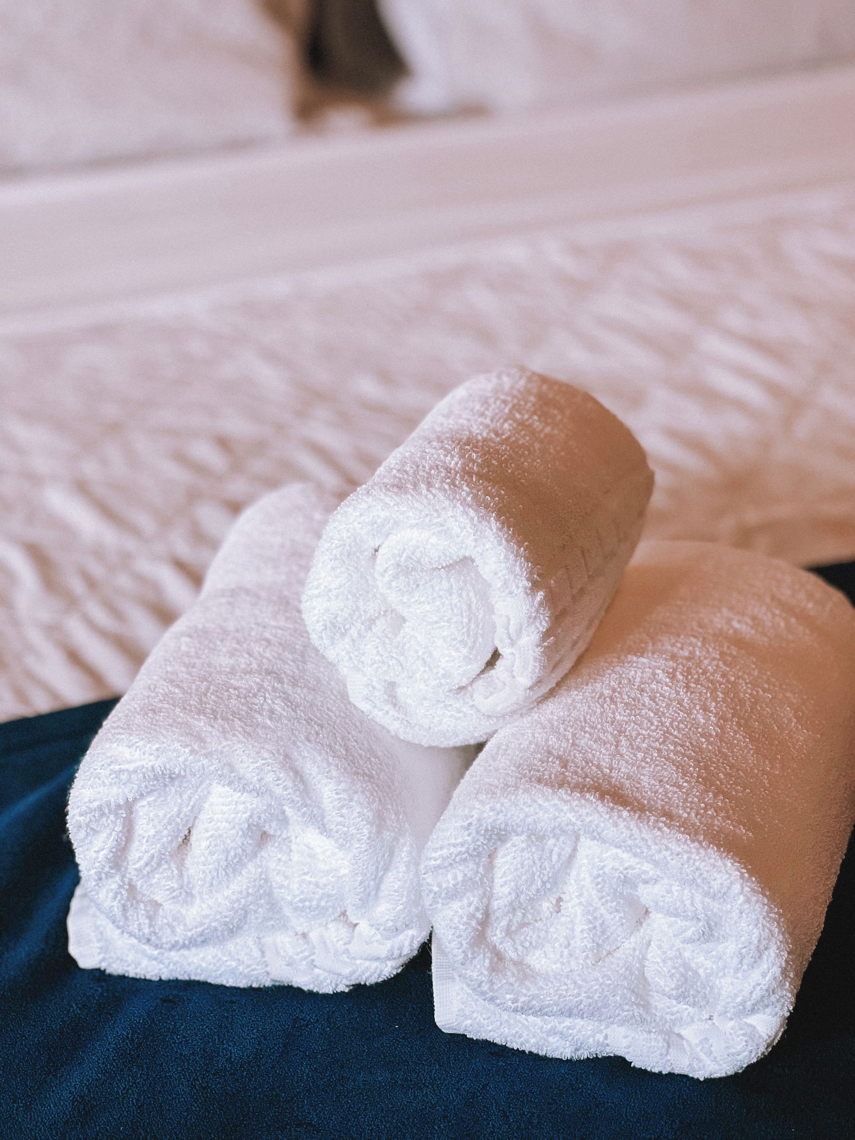 Two rolled white towels on a dark blue bedspread.
