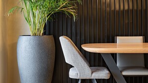 A modern dining area with a large potted plant, a wooden table, and chairs. - ICONIC SALONICA SUITE seafront (Thessaloniki)