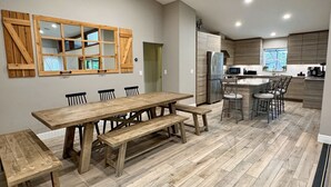 Een moderne keuken met houten kasten, een roestvrijstalen koelkast en een eethoek met een houten tafel en bankjes.