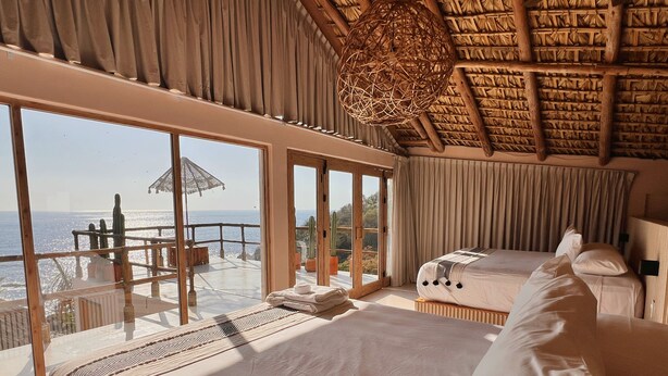 A room with a large bed, a smaller bed, and a balcony with a view of the sea. - Xeno Hotel Boutique (San Pedro Pochutla)