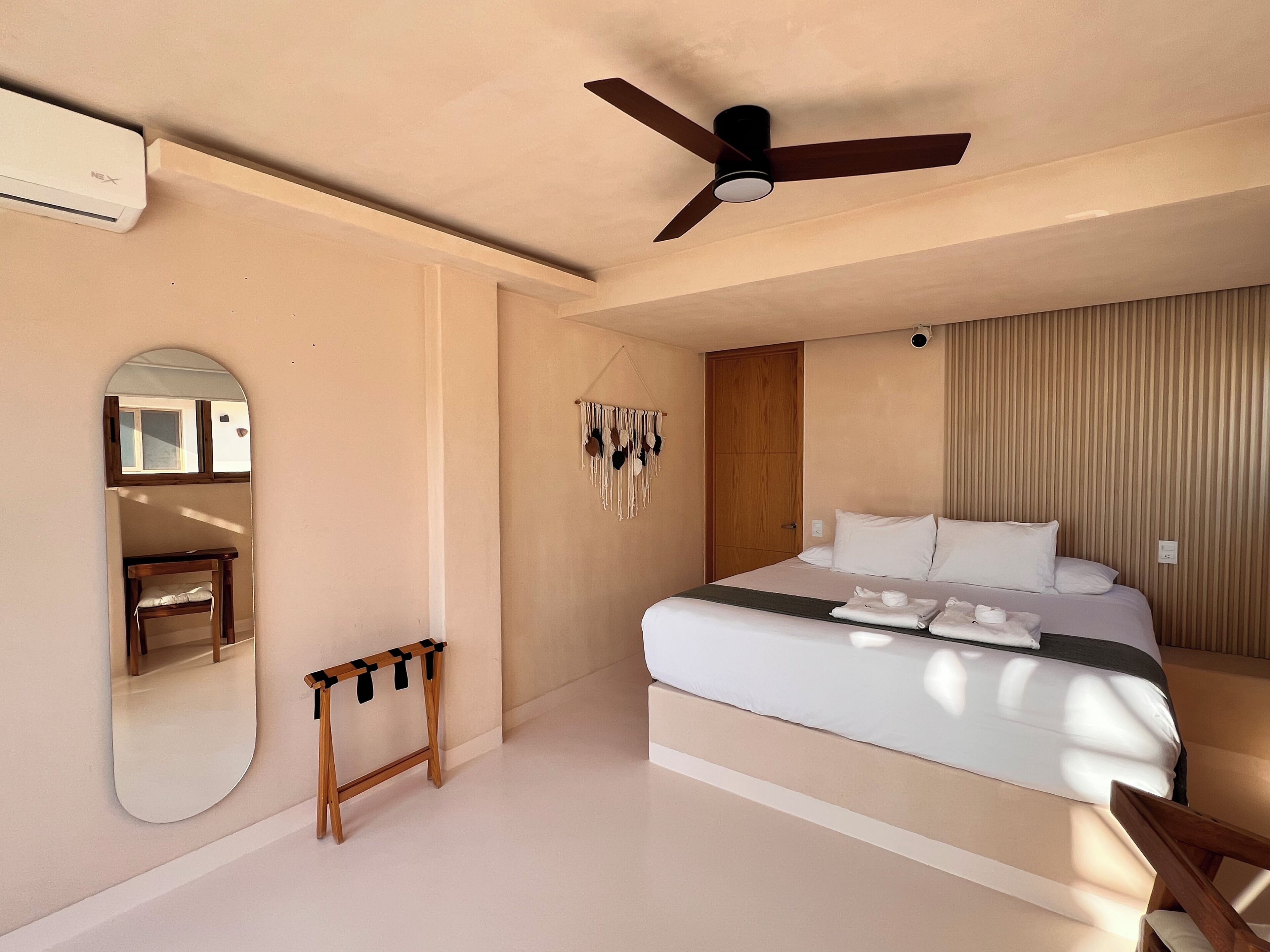 A bedroom with a bed, a ceiling fan, a mirror, and a wardrobe.
