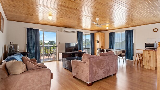 Ein geräumiges Wohnzimmer mit Holzboden, einem Flachbildfernseher, einer Couch und einem Essbereich mit Tisch und Stühlen.