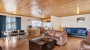 Ein gemütliches Wohnzimmer mit Holzbalkendecke, einer Couch, einem Couchtisch und einem Essbereich mit Stühlen und Tisch.