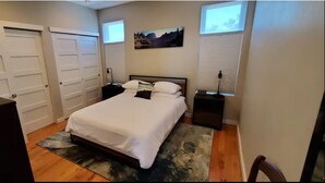 A bedroom with a bed, a desk, and a chair. There are two doors and a window with blinds. - Highlands Home with Rocky Mountain Views! (Denver)