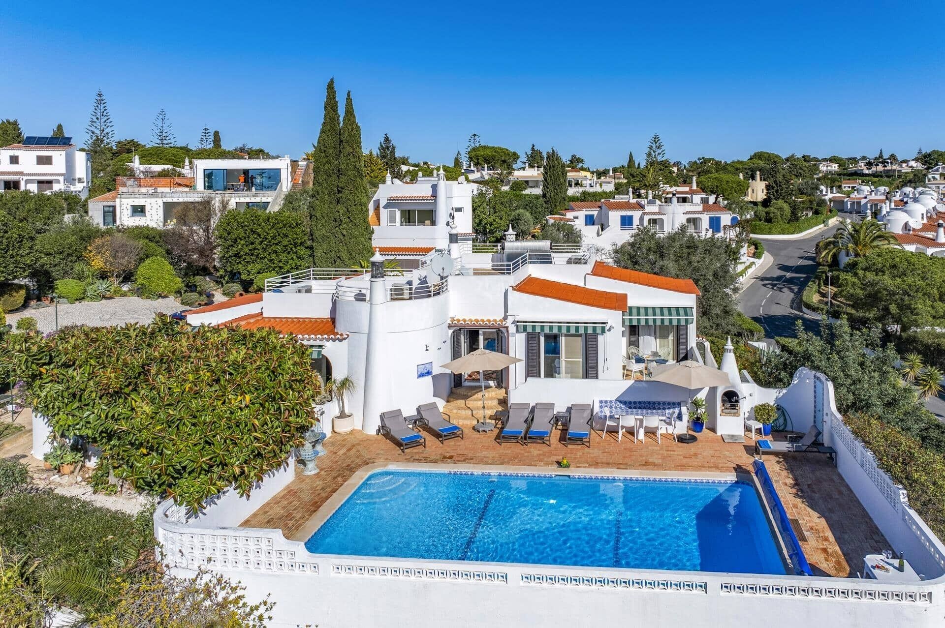 En modern villa med en pool på taket, vita väggar och rödfärgade takpannor.