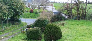 A rural landscape with a road, greenery, and a building in the background.