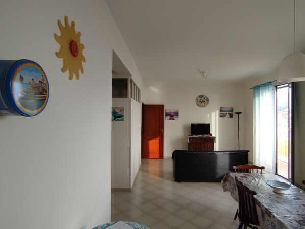 A spacious living area with a dining table, a TV, and a sofa.
