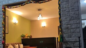 A room with a stone wall, a sofa, a coffee table, and a 'Welcome' sign. - Little Sikkim Inn (Gangtok)