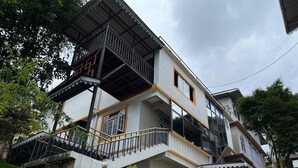 A multi-story residential building with a balcony on the upper floor, a staircase leading to the entrance, and a green hedge in the foreground. - Little Sikkim Inn (Gangtok)