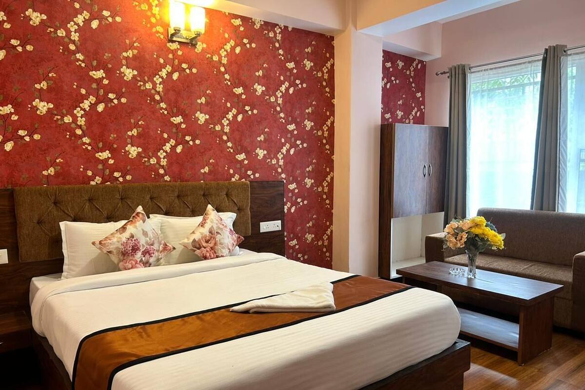 Une chambre d’hôtel avec un grand lit, une tête de lit en bois, un canapé, une table basse et un miroir.