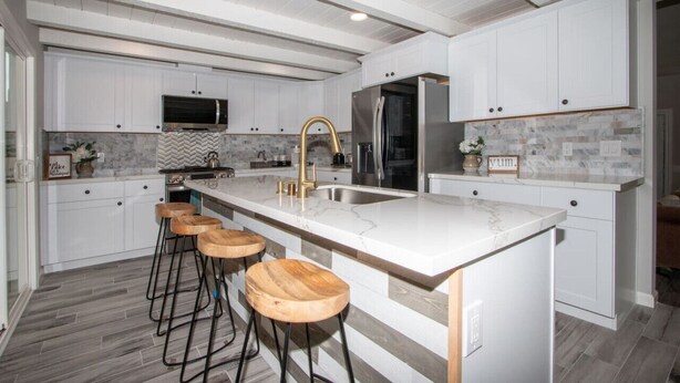 A modern kitchen with white cabinetry, a marble countertop, and wooden bar stools. - Fallbrooks Finest Hideaway Villa - Pool, Game Room (Fallbrook)