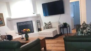 A living room with a fireplace, a flat-screen TV mounted on the wall, and a green sofa. - North Phoenix Beautiful Home. Huge Pool. Same events okay. (Phoenix)
