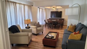A modern living room with a sofa, armchair, coffee table, and a dining area with chairs and a TV. - North Phoenix Beautiful Home. Huge Pool. Same events okay. (Phoenix)