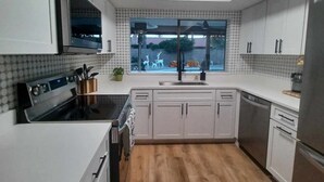 A modern kitchen with white cabinets, a stainless steel refrigerator, and a window with a view of the outdoors. - North Phoenix Beautiful Home. Huge Pool. Same events okay. (Phoenix)