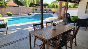 A covered patio with a pool, wooden table and chairs, and a grill area. - North Phoenix Beautiful Home. Huge Pool. Same events okay. (Phoenix)