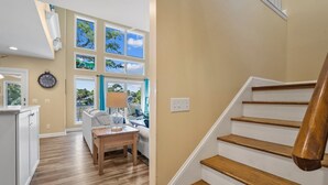 Une cuisine moderne avec un plan de travail en bois, un coin repas avec une table et des chaises, une horloge au mur et un escalier avec des marches en bois.