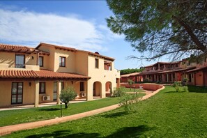 A courtyard with a building featuring a tiled roof and arched windows.