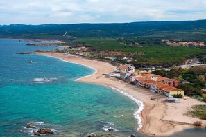 A coastal area with a beach, buildings, and a road.