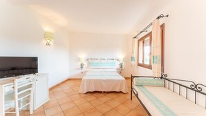 A bedroom with a bed, a desk with a chair, a television, and a window with curtains. - Apartment in Vignola Mare near Sandy Beach (Vignola Mare/Aglientu (SS))