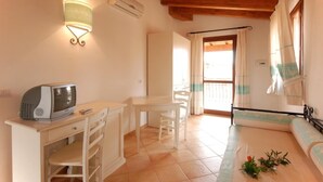 A room with a kitchenette, a dining area, a sofa, and a window with curtains. - Apartment in Vignola Mare near Sandy Beach (Vignola Mare/Aglientu (SS))
