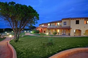 A multi-story building with a well-maintained lawn and a pathway leading to the entrance.