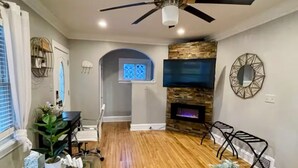 Un salon moderne doté d’un ventilateur de plafond, d’une cheminée, d’un téléviseur et d’une table basse en verre.