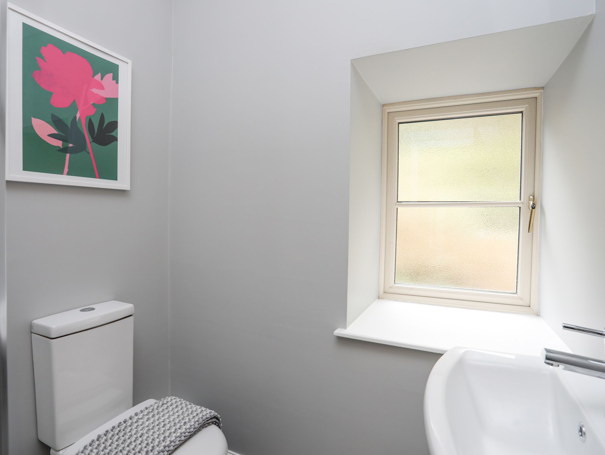 Un baño con inodoro, lavabo y ventana.