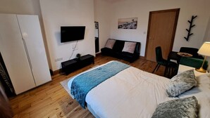 Ein Schlafzimmer mit Bett, Fernseher, Schreibtisch und Stuhl.