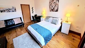 Ein Schlafzimmer mit Bett, Nachttischen, einem Schreibtisch und einer Couch.