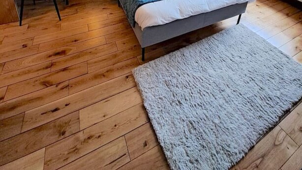 Ein Schlafzimmer mit einem Bett, zwei Nachttischen mit Lampen, einem Schreibtisch mit Stuhl, einem großen Fenster mit Vorhängen und einem Löwenbild an der Wand.