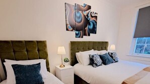 A hotel room with two beds, a large abstract painting on the wall, and a window with a view. - Kings X & Angel Haven (Greater London)
