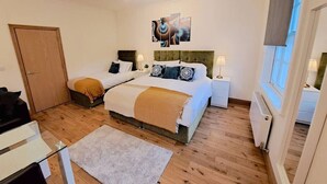 A bedroom with two beds, a wooden floor, a white radiator, and a window with a view. - Kings X & Angel Haven (Greater London)