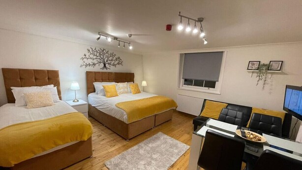 A room with two beds, a desk with a computer, a chair, and a window. - Kings Cross St Pancras Oasis (Greater London)