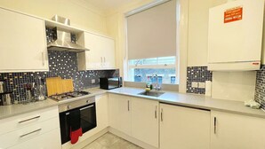 A modern kitchen with white cabinets, a gas stove, a microwave, and a sink. - Kings Cross St Pancras Oasis (Greater London)
