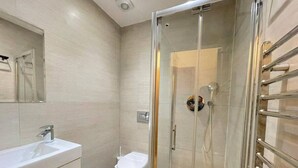 A modern bathroom with a glass-enclosed shower, a white sink, and a toilet. - Kings Cross St Pancras Oasis (Greater London)