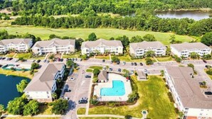 A residential area with apartment buildings, a swimming pool, and a lake.