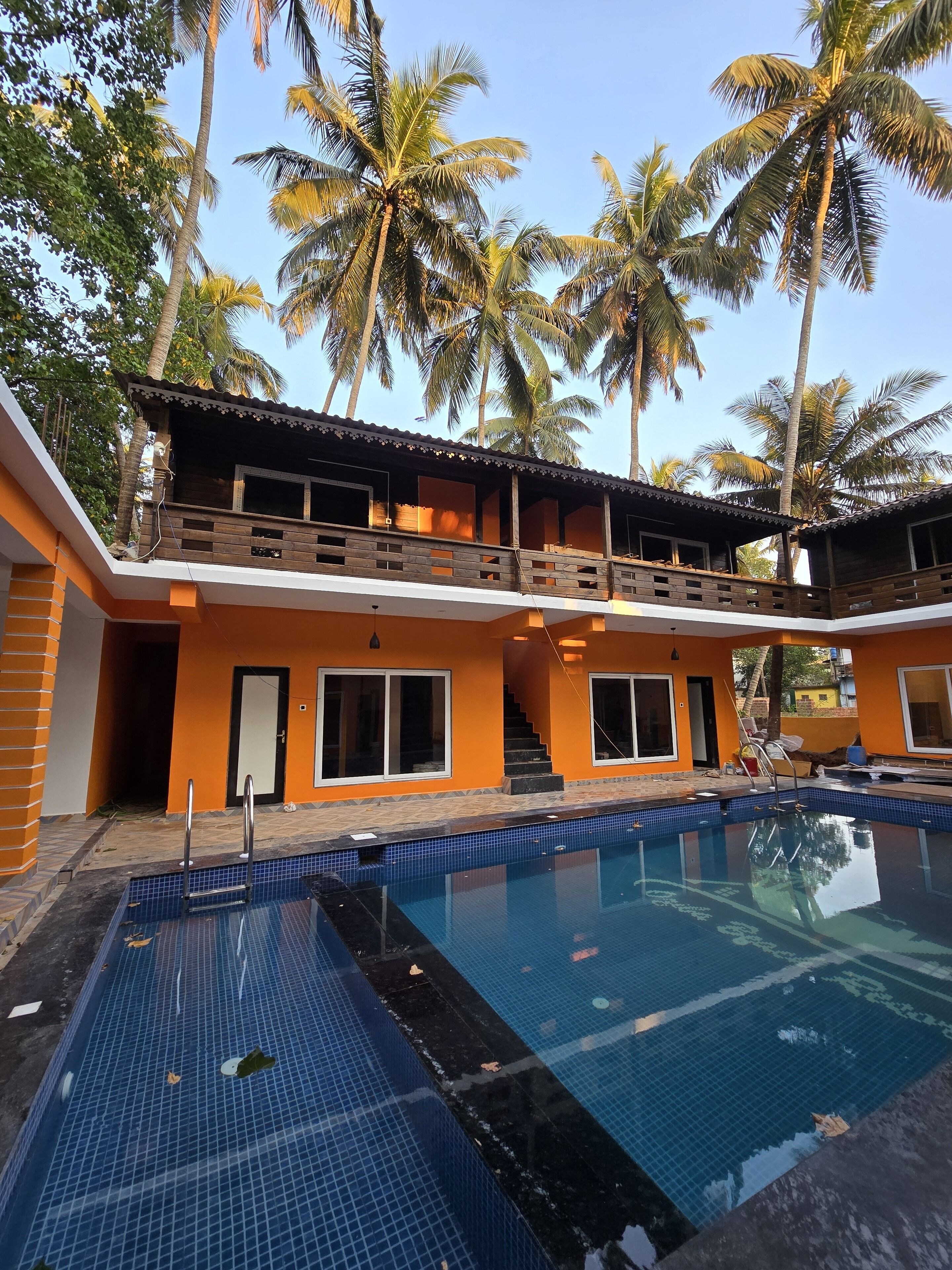 A two-story building with a swimming pool, surrounded by palm trees.