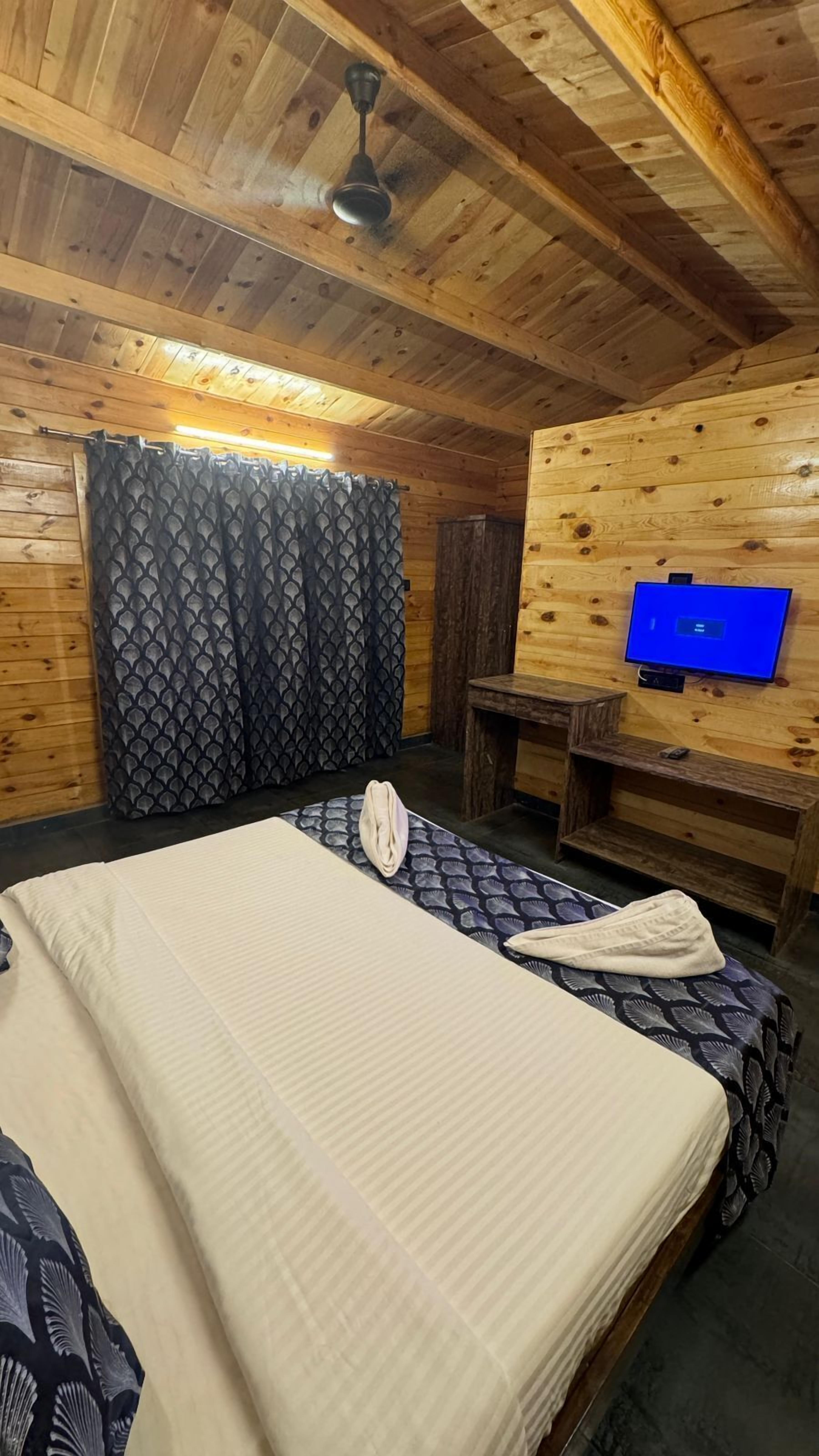 Una habitación de cabaña de madera con cama, televisión y una pequeña mesa.